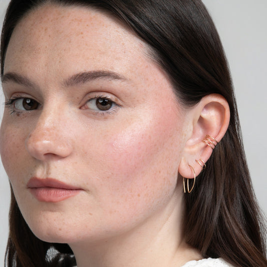 Close-up sideview of woman wearing earring stack with Half Moon Hammered Threader Earrings, Journey of Hope Huggie Earrings and Ear Cuff in 14k Gold Filled.