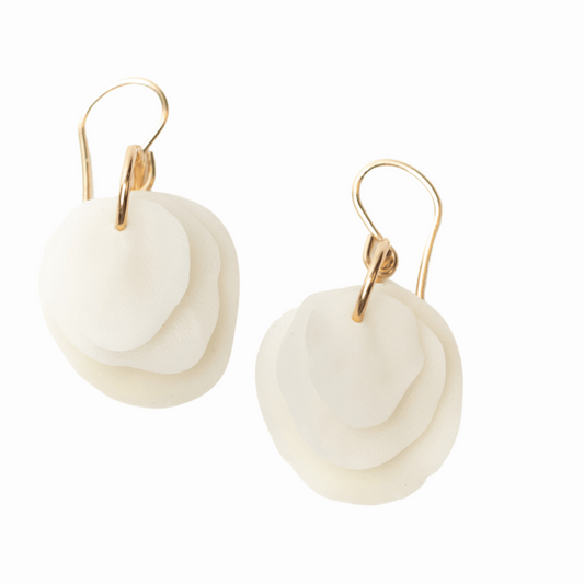 A woman wearing a pair of porcelain earrings with three layers of circular design dangling from a small 14k gold filled hoop on a fishhook ear wire.