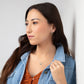 Woman in denim jacket with umber blouse wearing Moab Western Beaded Necklace and Earrings in Sterling Silver. Horseshoe pendant. Hoop, threader earrings with turquoise beads.