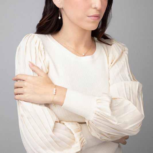 A woman showcasing the classic Leeda Freshwater Pearl Bracelet in 14k Gold Filled on her wrist.