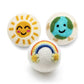 Three colorful reusable dryer balls with sun, planet, and rainbow designs on a white background.