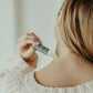 Person applying Thistle Farms Rest essential oil roll-on to their neck.
