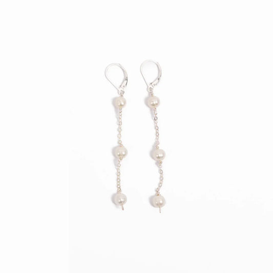 Woman in a blue pleated blouse wearing freshwater pearl triple drop leverback earrings in sterling silver