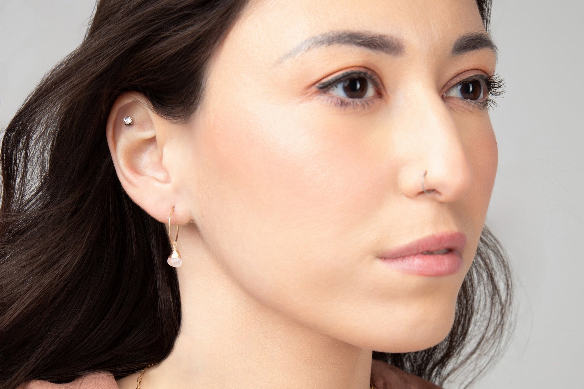 Woman wearing a gold necklace against a neutral background