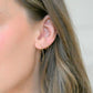 close up of an ear wearing simple gold hoop earrings
