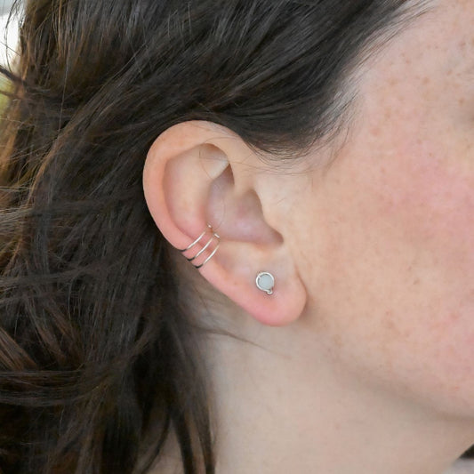 Pair of silver stud earrings with light green gemstone beads on a white background
