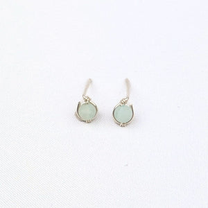 Pair of silver stud earrings with light green gemstone beads on a white background