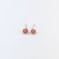 Pair of gold stud earrings with pink gemstones on a white background