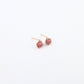 pair of gold stud earrings with pink beads in the center on a white background