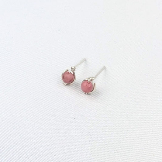a pair of silver stud earrings with pink beads on a white background