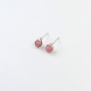 a pair of silver stud earrings with pink beads on a white background