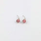 a pair of silver stud earrings with pink beads on a white background