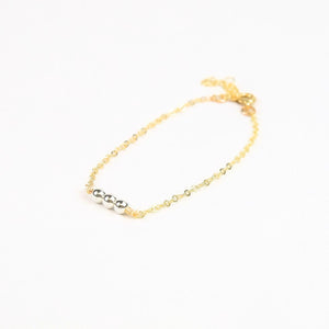 Gold bracelet with 3 silver beads on a white background