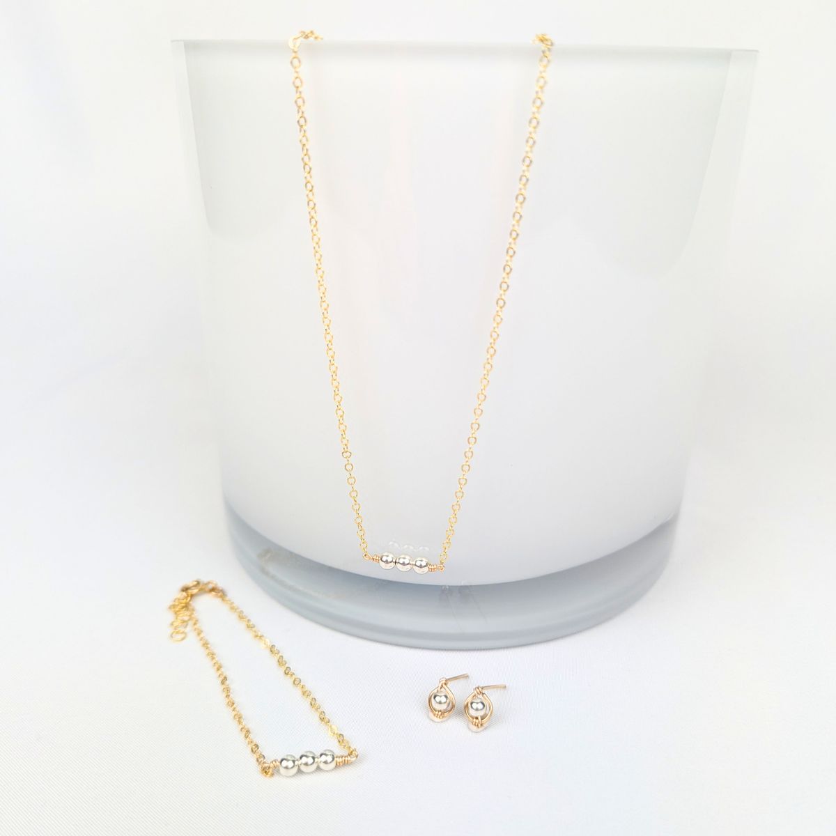 gold necklace, bracelet and earrings, all adorned with silver beads, on a white background