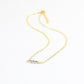 Gold necklace with three silver beads on a white background
