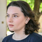 Woman with short dark hair wearing forai mingle mixed metal stud earrings and a necklace, outdoors.