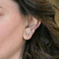 close up of an ear wearing forai mingle mixed metal stud earrings, forai journey of hope huggie earrings in gold, and forai journey of hope ear cuff in sterling silver