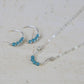 a sterling silver necklace with a horseshoe pendant featuring tiny turquoise beads with matching small hoop earrings on a stone surface
