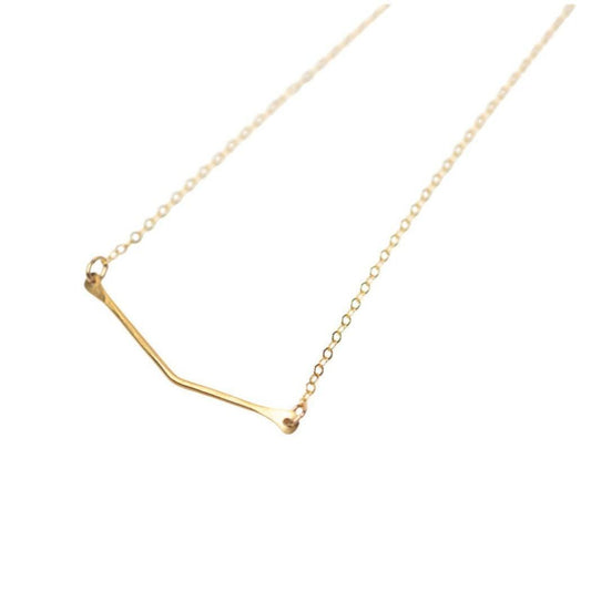 A woman wearing a maroon leather shirt and a 14k gold filled chain necklace with a brass chevron pendant.