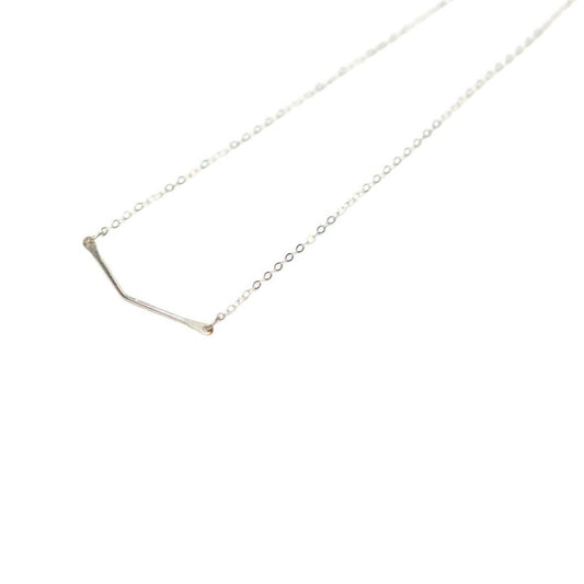 A woman in a blue denim shirt showcasing a sterling silver chevron pendant necklace.