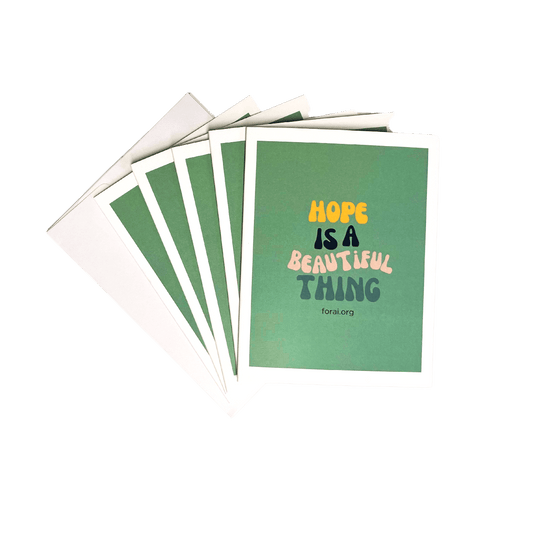 A lagoon blue notecard with the inspirational message 'Hope is a beautiful thing' written in multi-colored text, accompanied by an envelope.