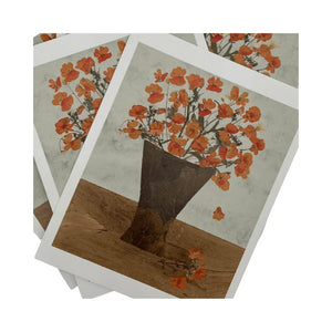 Stack of greeting cards with floral design and brown vase made from dried and handcut botanicals on a white background