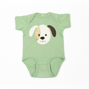 Sage green baby onesie with handmade puppy applique, one brown ear and one white ear, spotted patch over one eye.