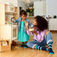 Woman and child in a kitchen, with the woman holding a small object and the child reaching out.