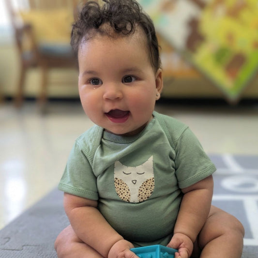 Green baby onesie with a owl design on a white background