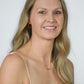 blond woman wearing pink rhodonite beaded earrings and necklace in gold with a yellow sundress
