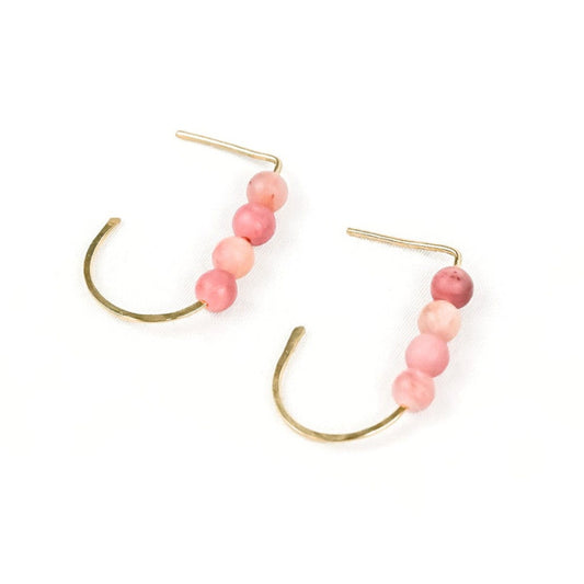 a pair of gold j-shaped earrings each with four pink stone beads on a white background