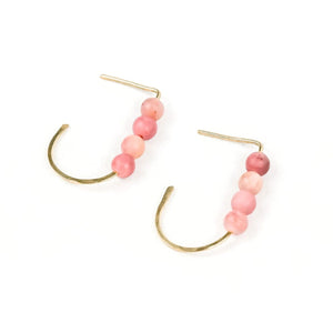 a pair of gold j-shaped earrings each with four pink stone beads on a white background