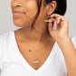 A young woman wearing the Samira Seeds of Hope Necklace and Earrings in 14k Gold Filled featuring a brass circle pendant with white and gold seed beads across the center.