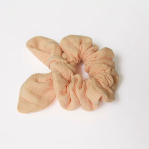 a peach scrunchie made of double cotton guaze on a white background