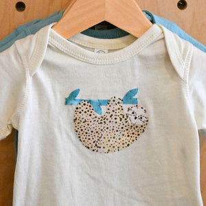 close-up of sloth design on natural baby onesie