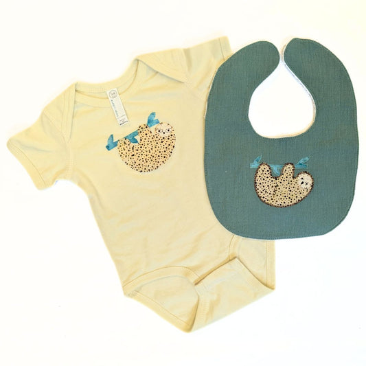 Green baby bib with a sloth design on a white background