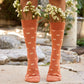 Legs of person wearing orange crew socks with white butterflies and small bouquets of flowers tucked in the top of the socks.