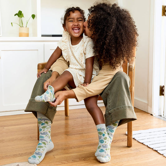 Pair of socks with sloth and leaf pattern on a white background