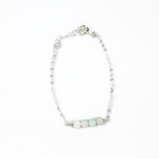 sterling silver chain bracelet with four round amazonite beads at the center on a white background