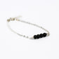 silver chain bracelet with four black onyx beads on a white background
