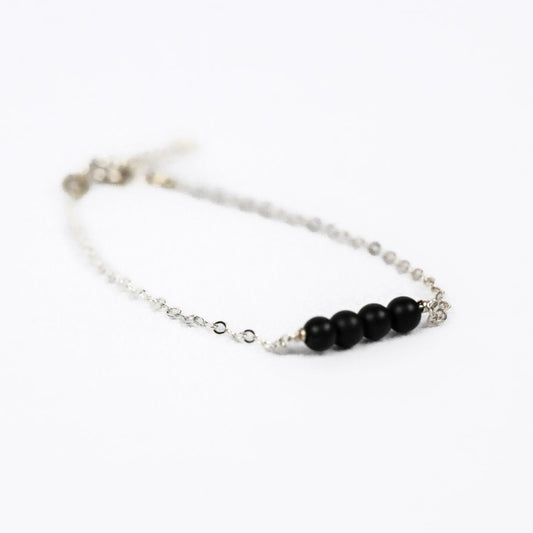 silver chain bracelet with four black onyx beads on a white background