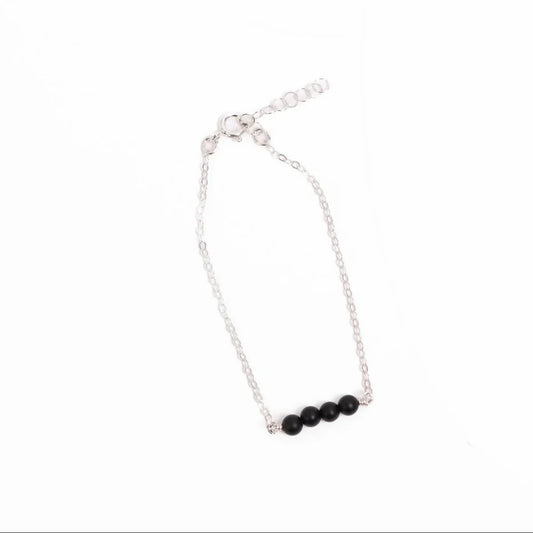 Sterling silver bracelet with black onyx beads on a white background