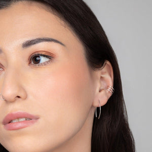 A close-up image of a woman's ear wearing the Qasioun Mini-threader Earring in sterling silver.