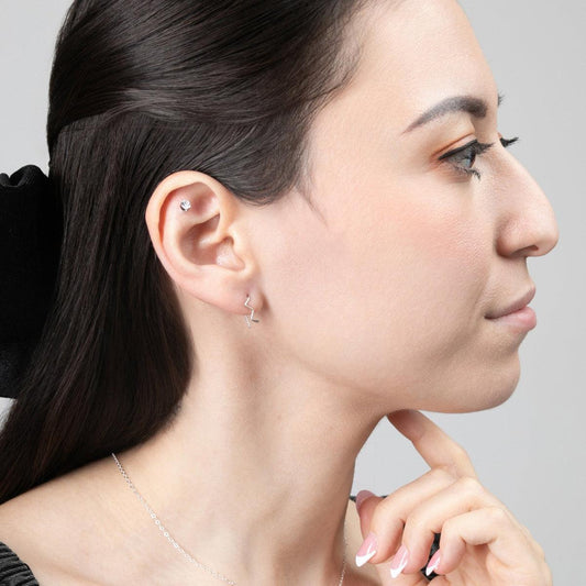 A young woman wearing Zun Zuun Threader Earrings in sterling silver. Earrings have a geometric, zig-zag design.