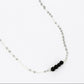silver chain link necklace with four black onyx beads at the center on a whilte background