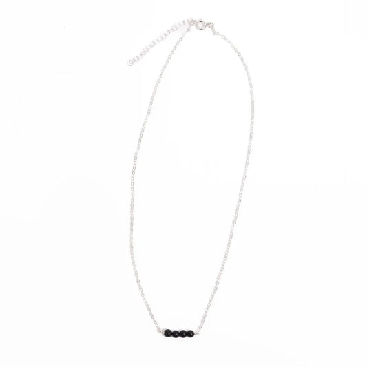 Sterling silver minimalist necklace with black onyx beads on a white background
