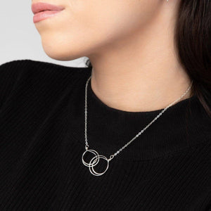 The Zomi Circles of Unity Necklace, a sterling silver necklace featuring interlocking circles, worn by a person in a black sweater.