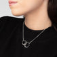 The Zomi Circles of Unity Necklace, a sterling silver necklace featuring interlocking circles, worn by a person in a black sweater.