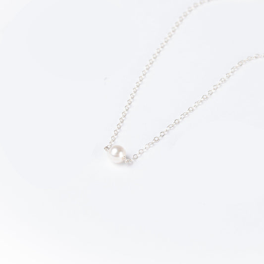 A woman in a black top wearing the Leeda Pearl Necklace in Sterling Silver which features a single freshwater pearl