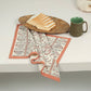 Patterned cloth on a table with bread and a mug